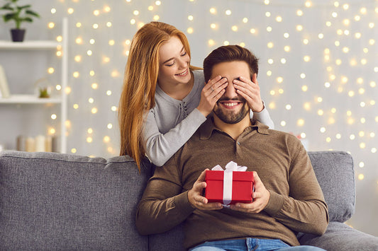 Smiling young woman covering her boyfriends eyes