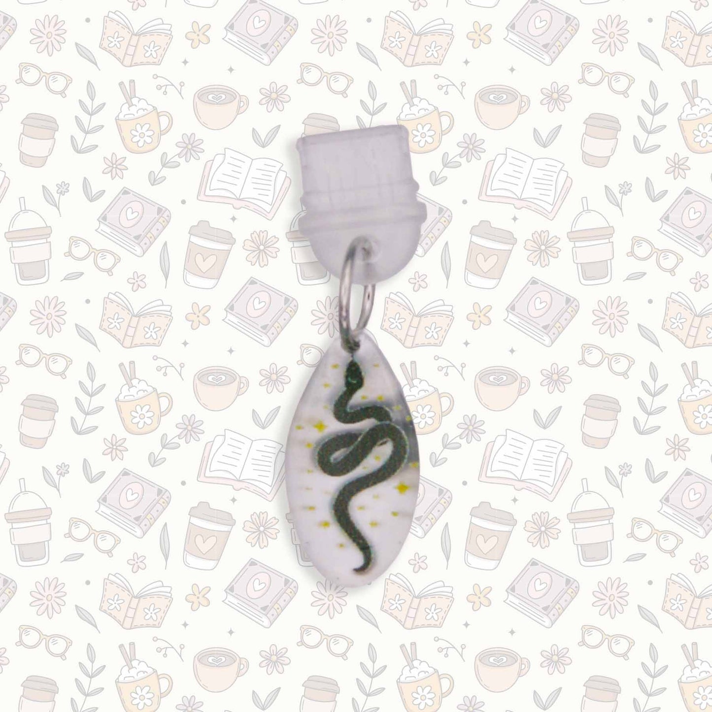 Celestial Snake Kindle Charm with black snake design on pearlescent acrylic, USB-C dust plug, shown on patterned background