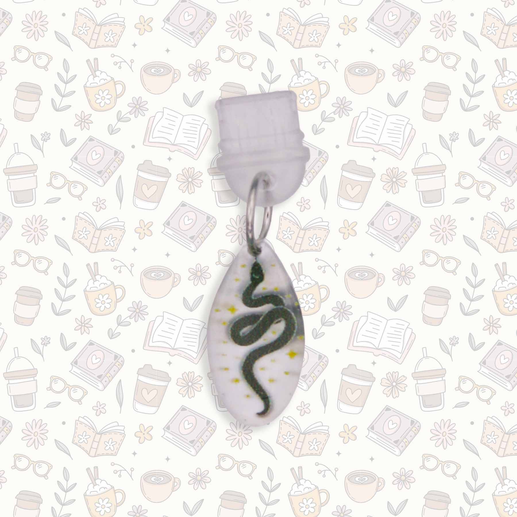 Celestial Snake Kindle Charm with black snake design on pearlescent acrylic, USB-C dust plug, shown on patterned background