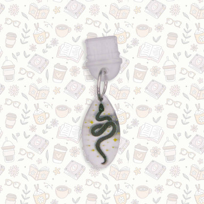 Celestial Snake Kindle Charm with black snake design on pearlescent acrylic, USB-C dust plug, shown on patterned background