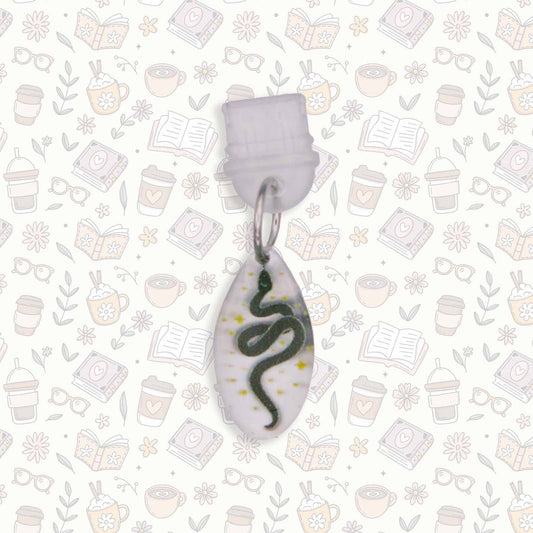 Celestial Snake Kindle Charm with black snake design on pearlescent acrylic, USB-C dust plug, shown on patterned background