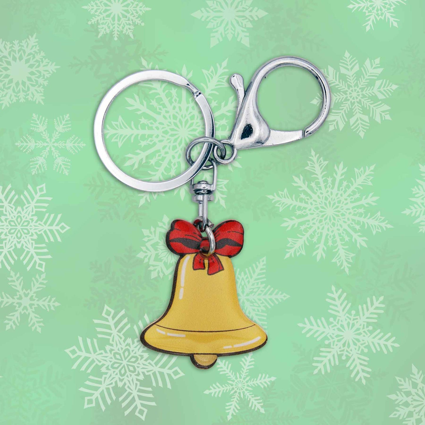 Christmas jingle bell bag charm keychain with red bow on a green snowy background.