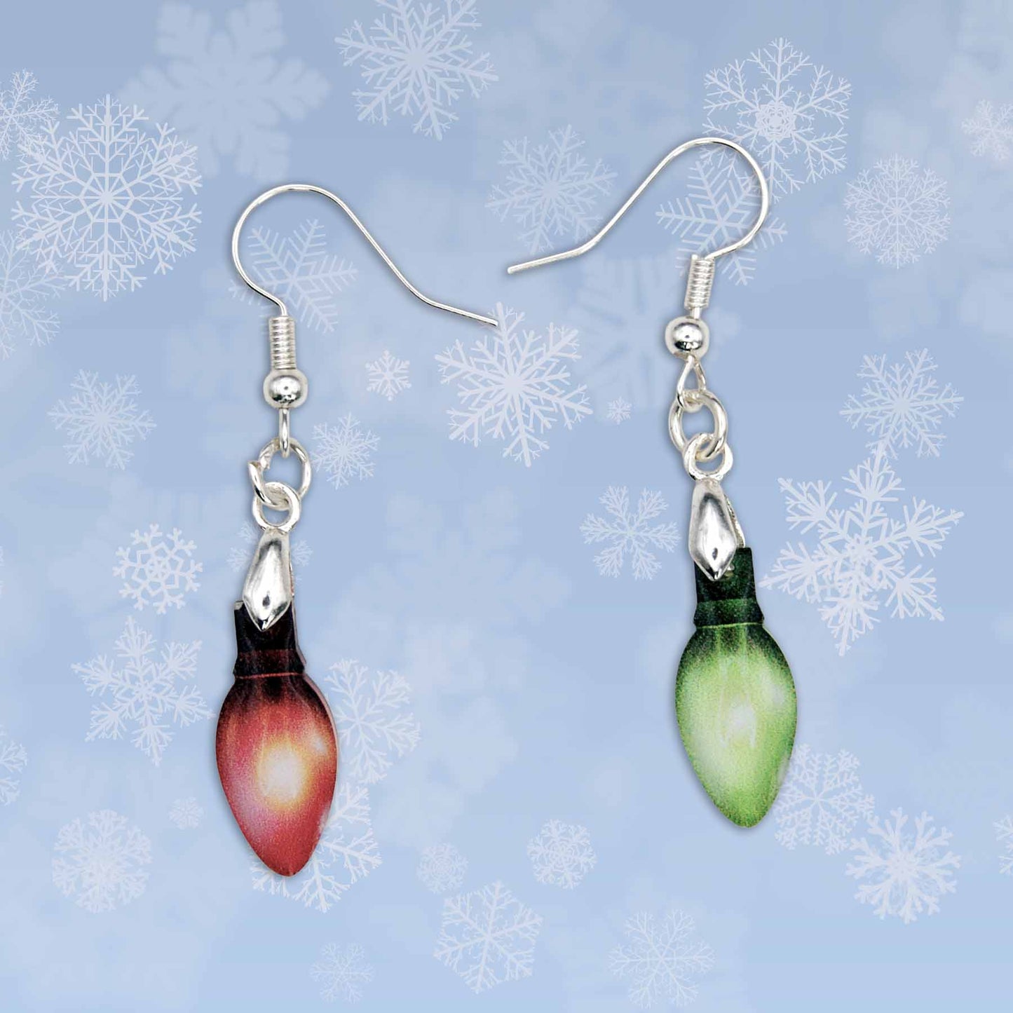 Christmas light bulb dangle earrings; one red, one green, with silver hooks, against a blue snowflake background.