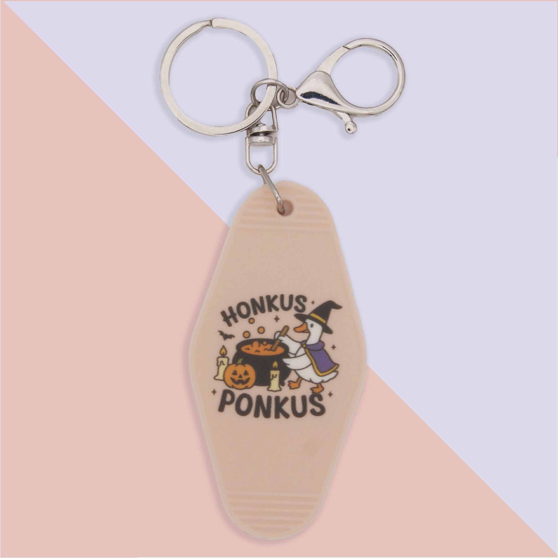 Honkus Ponkus Halloween keychain with a witch duck stirring a cauldron, alongside a pumpkin and candles.