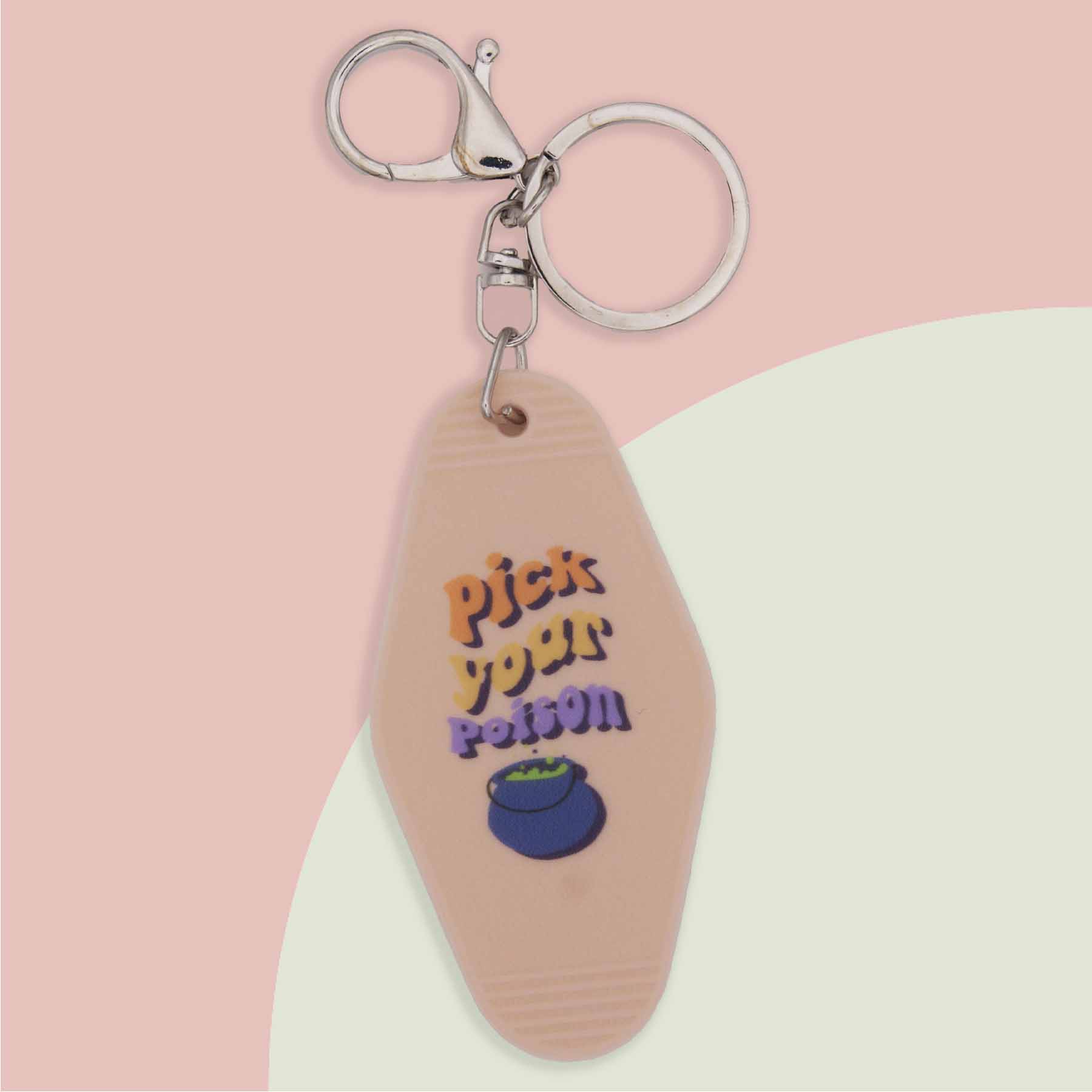 Peach colored hotel-style keychain with "Pick Your Poison" in colorful text, a blue cauldron, and a silver keyring.