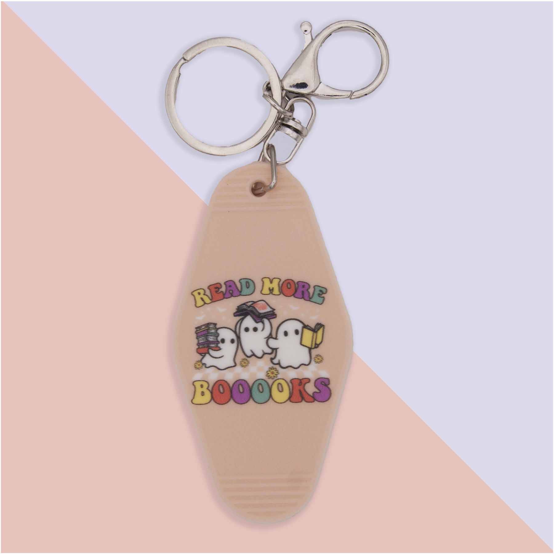 Tan motel-style keychain with silver hardware. Features three cartoon ghosts and the text 'READ MORE BOOOOKS'. One ghost holds books, another wears glasses, and the third reads a book.