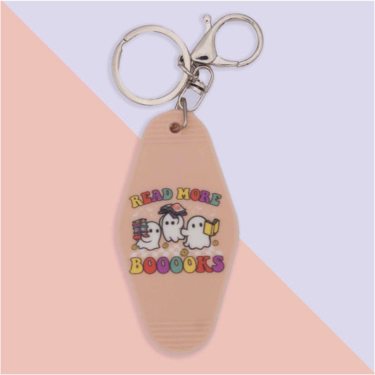 Tan motel-style keychain with silver hardware. Features three cartoon ghosts and the text 'READ MORE BOOOOKS'. One ghost holds books, another wears glasses, and the third reads a book.