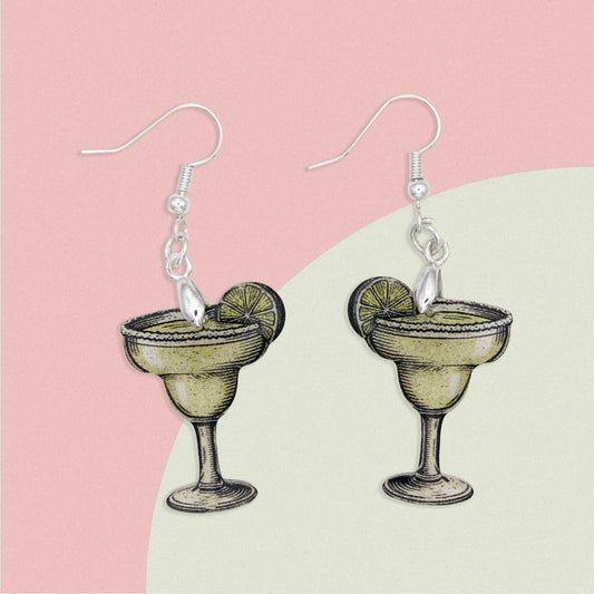 Pair of margarita cocktail drop earrings with lime slice detail and silver hooks on a pink and green background.