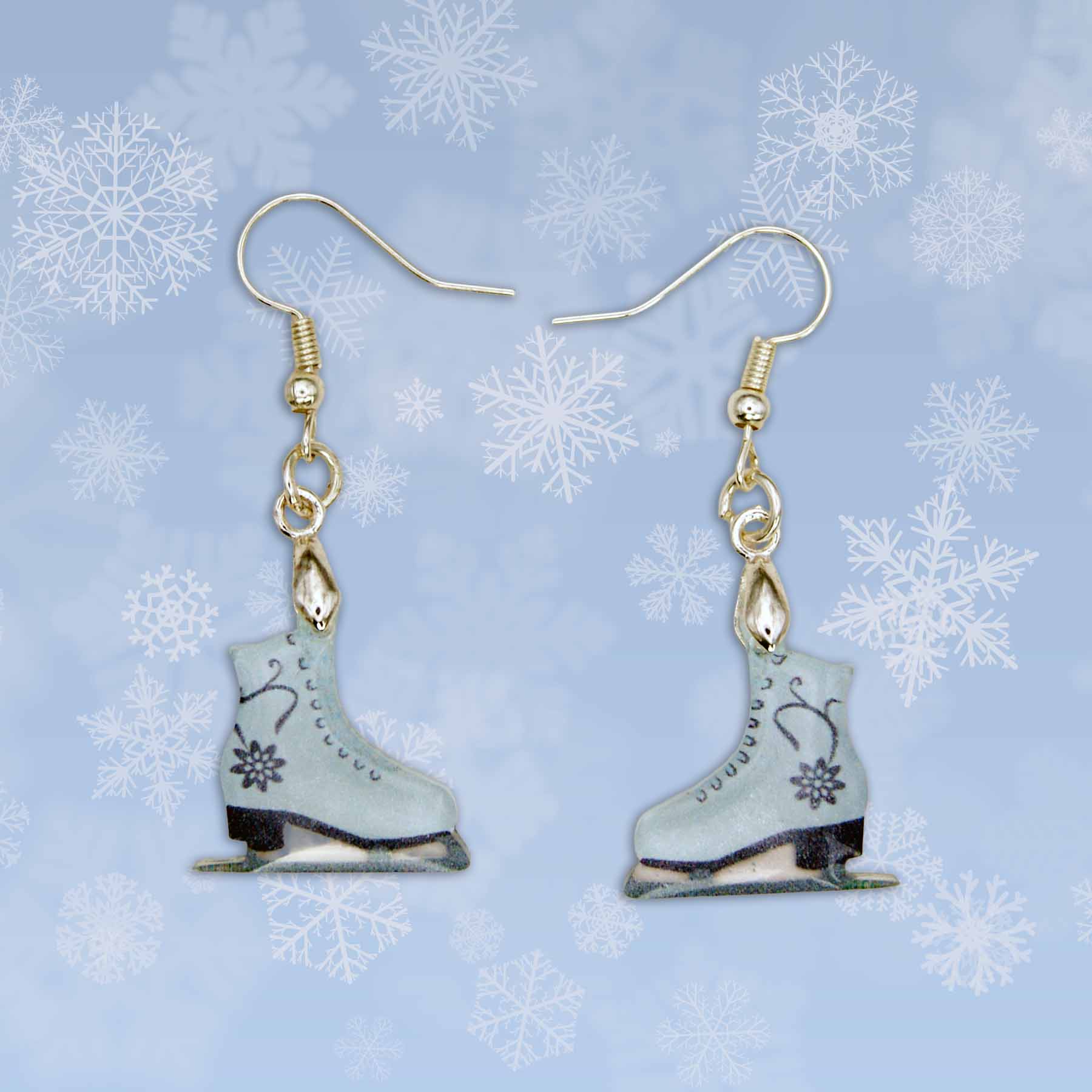 A pair of light blue ice skate dangle earrings with black floral designs. Gold-toned hooks are attached to the top of each skate, which feature black blades and black heels.
