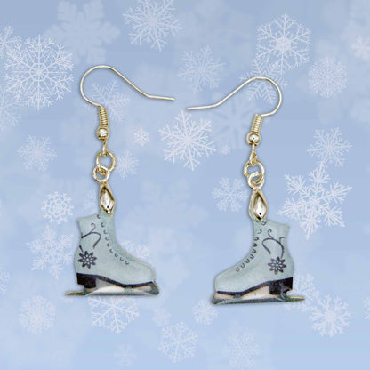 A pair of light blue ice skate dangle earrings with black floral designs. Gold-toned hooks are attached to the top of each skate, which feature black blades and black heels.