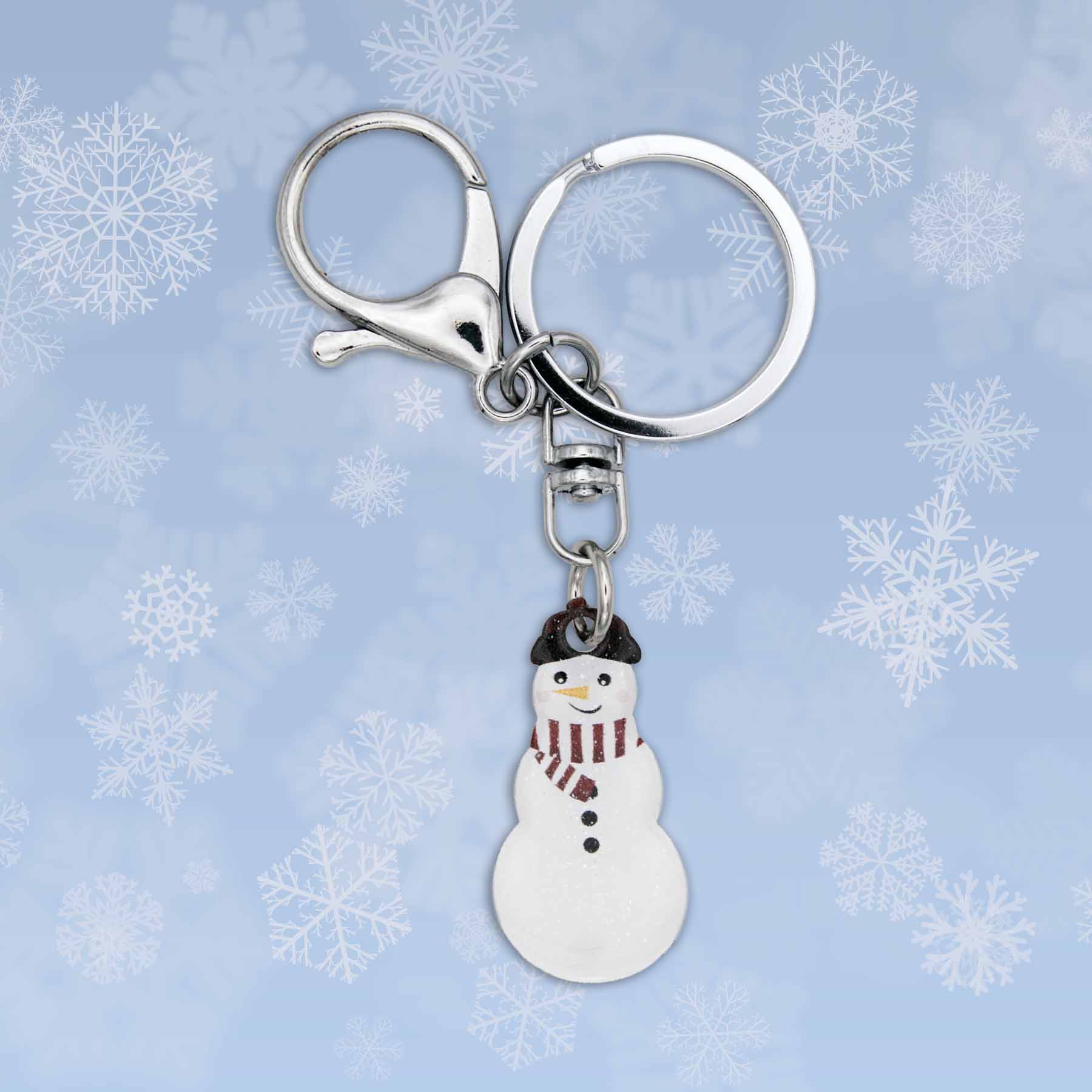 Winter snowman bag charm keychain with silver clasp and keyring against a blue snowflake background.
