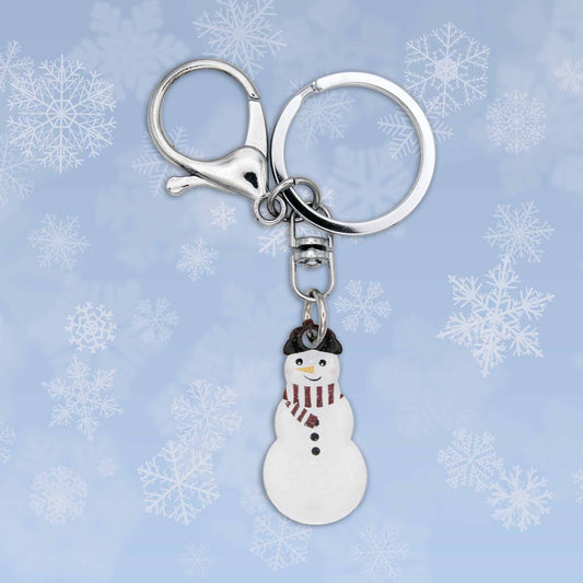 Winter snowman bag charm keychain with silver clasp and keyring against a blue snowflake background.